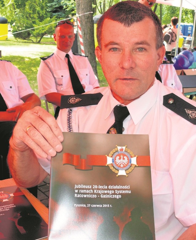 Druh Ryszard Szado - komendant gminny Ochotniczej Straży Pożarnej w Pysznicy, prezentuje jubileuszowe wydawnictwo.