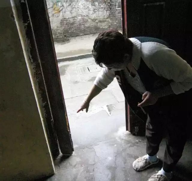 Pani Krystyna pokazuje zniszczone przez małoletnich wandali drzwi na klatce schodowej.