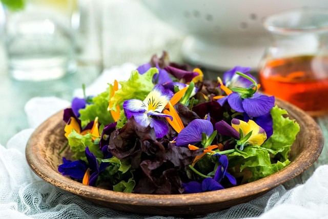 Sałatki z owoców i warzyw nie tylko mają pozytywny wpływ na naszą urodę i zdrowie, ale także są bardzo proste w przygotowaniu. Na zdjęciu sałatka z letnich liści sałat i kwiatów z ostrym dressingiem.