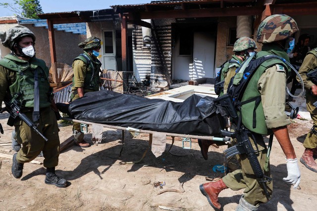 Izraelscy wojskowi wynoszą ciała zabitych mieszkańców kibucu.