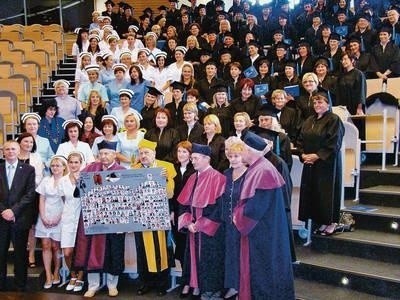 Całe grono tegorocznych absolwentek i absolwentów z władzami uczelni i pamiątkowym tablo Fot. Anna Szopińska