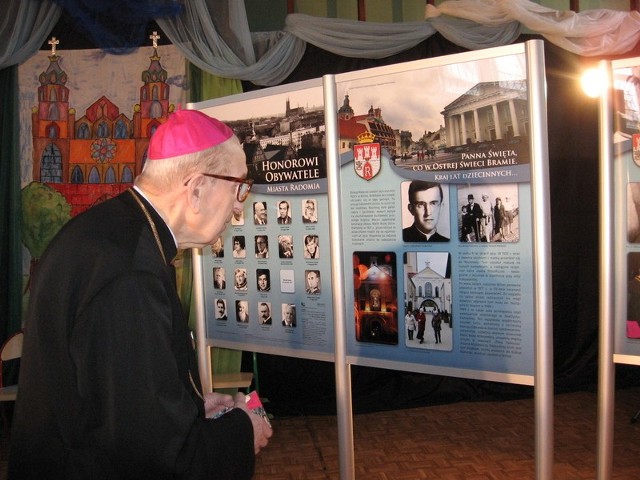 Ksiądz biskup Edward Materski dokonał symbolicznego otwarcia wystawy. Stoi obok swojej fotografii z młodości.