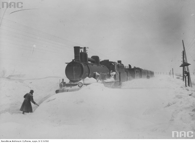 Odśnieżanie tor&oacute;w na trasie Lw&oacute;w - Przemyśl. Pociąg pasażerski ciągnięty przez parow&oacute;z Tr 11 na zasypanych torach.Data wykonania zdjęcia: 1919 - 1939Zdjęcie dzięki uprzejmości Narodowego Archiwum Cyfrowego.