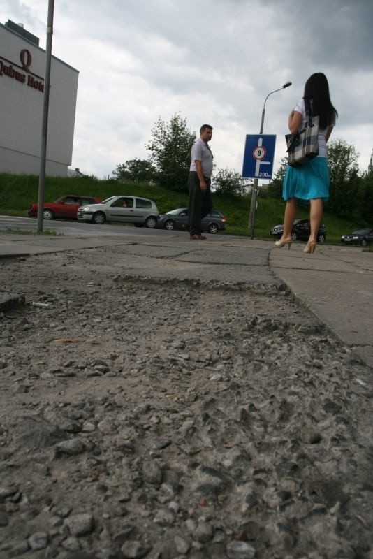 Wyrwa w chodniku znajduje się tuż przy ulicy. Na potrzaskanych płytkach łatwo się potknąć.