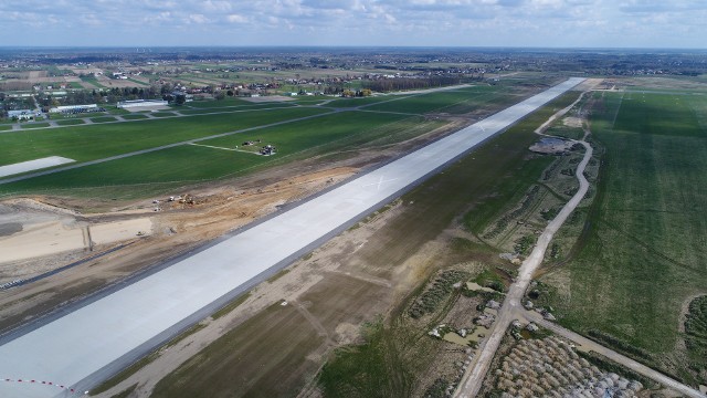 Praktycznie z dnia na dzień widać duże postępy na budowie Portu Lotniczego Warszawa &ndash; Radom. Nie ma op&oacute;źnień w stosunku do harmonogramu prowadzenia inwestycji i wszystko wskazuje na to, że lotnisko będzie gotowe na przyjmowanie oraz odprawianie samolot&oacute;w w połowie przyszłego roku. Prace budowlane prowadzone są w r&oacute;żnych częściach lotniska, ale najbardziej widać postęp na budowie terminala, budynk&oacute;w magazynowych, przeznaczonych dla Straży Granicznej i celnik&oacute;w, a także na budowie wieży kontroli lot&oacute;w oraz strażnicy lotniskowej straży pożarnej. W całej okazałości widać już między innymi elewację terminala &ndash; nie tylko od strony parking&oacute;w, ale  r&oacute;wnież od strony płyt postojowych dla samolot&oacute;w. Ekipy budowlane r&oacute;żnych wykonawc&oacute;w widać też w otoczeniu pasa startowego oraz we wschodniej stronie lotniska &ndash; na budowie drogi kołowania przeznaczonej dla samolot&oacute;w  startujących od strony Małęczyna lub lądujących od strony miasta.Na kolejnych slajdach zobacz zdjęcia wykonane z drona z budowy lotniska wykonane pod koniec kwietnia &gt;&gt;&gt;