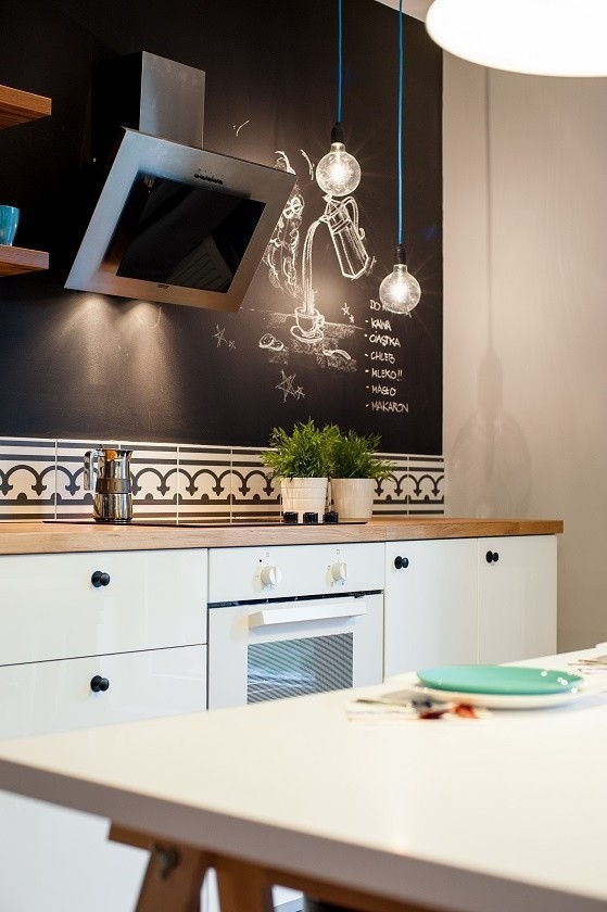 Farba tablicowa w kuchniFragment ściany pomalowany farbą tablicową pełni w tej kuchni funkcję zarówno dekoracyjną, jak i użytkową.