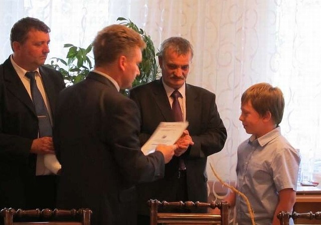 Stypendysta Bartosz Winnicki (z prawej) otrzymuje gratulacje z rąk burmistrza Jacka Tarnowskiego i przewodniczącego Rady Miejskiej Stanisława Lolo.