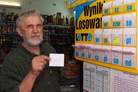 Krzysztof Markowski, właściciel sklepu, pokazuje wydruk z informacją o głównej wygranej w jego kolekturze