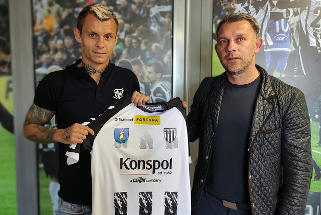 Kornel Osyra pozuje z koszulką Sandecji w towarzystwie wiceprezesa i dyrektora sportowego Sandecji Łukasza Skrzyńskiego