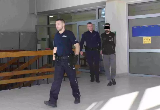 Oskarżony Arkadiusz C. w konwoju policyjnym jest doprowadzany do krakowskiego sądu