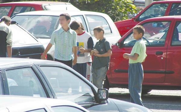 Dzieci z parkingu przy alei Niepodległości proszą kierowców o drobne na bułkę. Wielu z nich ulega i daje im pieniądze.