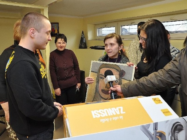 Podopieczna Warsztatów Terapii Zajęciowej przy alei Niepodległości w Tarnobrzegu, Monika Barszcz (z obrazem) dziękuje Wojciechowi Doktorowi (w czarnej bluzie), prezesowi Stowarzyszenia Sympatyków Piłki Nożnej "Złota Siarka&#8221; za zakup w ramach akcji "Siarkowcy Dzieciakom&#8221; aparatu słuchowego.