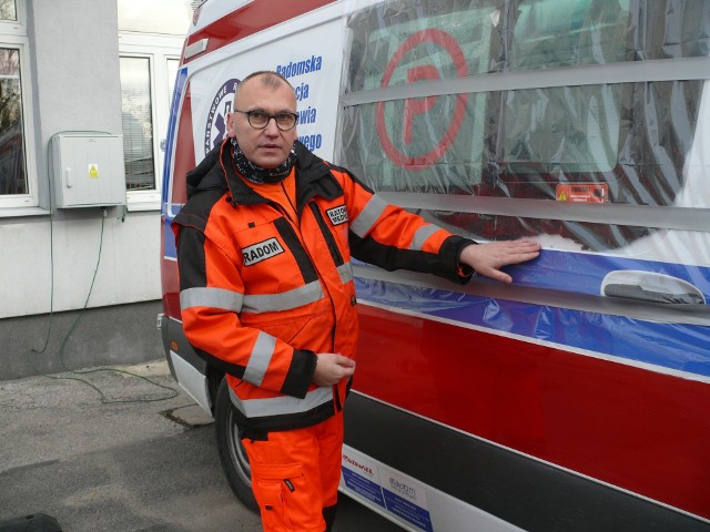 Mariusz Wielocha, ratownik Pogotowia Ratunkowego w Radomiu, w tle uszkodzona karetka.