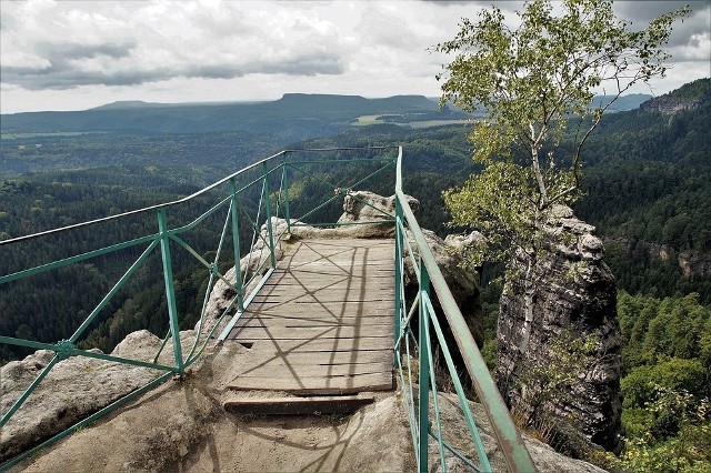 Zaledwie 100 km od południowej granicy województwa lubuskiego leży kraina, która zachwyci każdego. Podzielona granicą czesko-niemiecką oferuje paletę bogactwa doznań dla duszy i ciała. Dojedziemy tam, jadąc wzdłuż granicy polsko-niemieckiej i dalej kierując się na Jetřichovice. Park Narodowy České Švýcarsko - to obszar 79 km² pełen unikatowych form skalnych i rozległych obszarów o charakterystycznej krawędziowej rzeźbie terenu i naturalnych ekosystemach. Imponujące formy skalne budzą podziw i są geologicznym studium nawet dla laika. Wędrówka zdecydowanie przyjemna, bo przewyższenia są tu niewielkie, dlatego park polecany jest wszystkim bez względu na wiek i kondycję. Tu każdy może zostać zdobywcą pięknych widoków ze szczytu. Szczególnie charakterystycznymi miejscami są vyhlídky, co tłumacząc na język polski znaczy wyglądajki. Na zdjęciu właśnie jedna z nich. Najczęściej są one miejscami wysoko położonymi, a wychodzącymi widokiem na zapierającą dech malowniczą przestrzeń.Wideo: Boom na wakacje we wrześniu. Skąd się wziął?Źródło: Dzień Dobry TVN/x-news