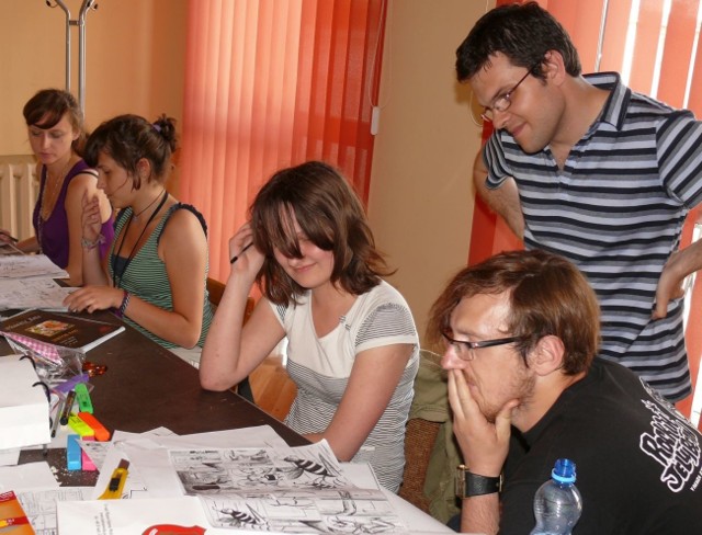 Przemysław Truściński i Kuba Woynarowski oceniają prace uczestników warsztatów komiksu.