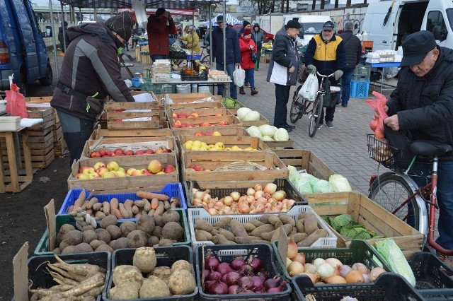 Na placu targowym na straganach pod chmurką jest kolorowo od owoców i warzyw