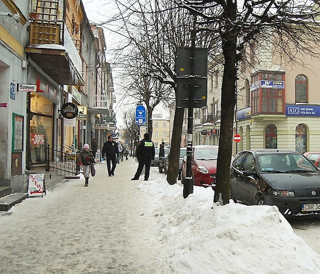W centrum Brodnicy, przy ul. Hallera straznicy miejscy kontrolują usuwanie śniegu z chodnikow.
