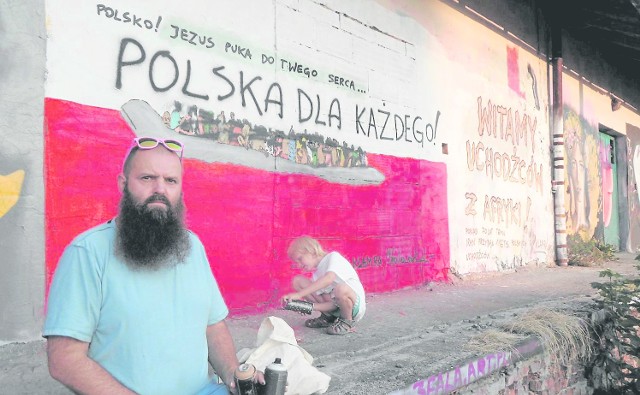 Dariusz Paczkowski z synem na tle zniszczonego muralu, który został już częściowo odnowiony