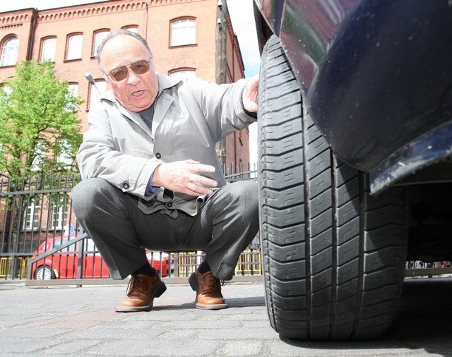 Eugeniusz Szydłowski obok samochodu, którym wjechał w roztopiony asfalt.