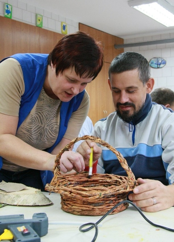 Elżbieta Szafrańska pomaga Norbertowi Szali w wyplataniu koszyka.