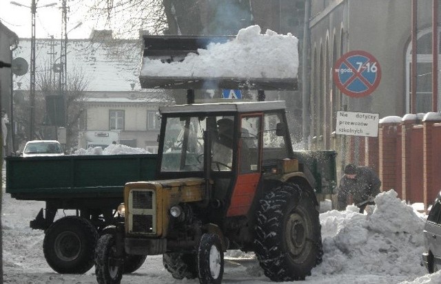 Ciągniki z przyczepami wywożą śnieg za miasto.