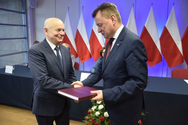 Minister Mariusz Błaszczak wręcza burmistrzowi Marianowi Burasowi księgę pamiątkową wraz z pierwszym wpisem, w którym znalazły się życzenia i gratulacje.