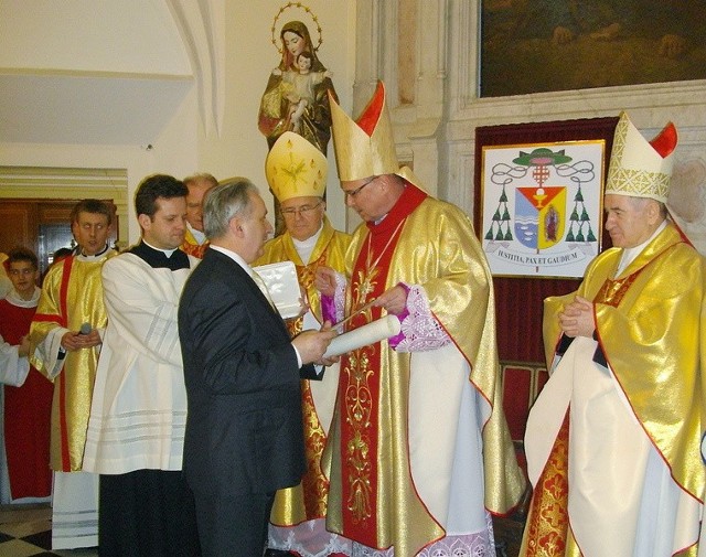 Eugeniusz Rakoca odbiera z rąk bpa Wiesława Alojzego Meringa dyplom związany z papieskim medalem Benemerenti