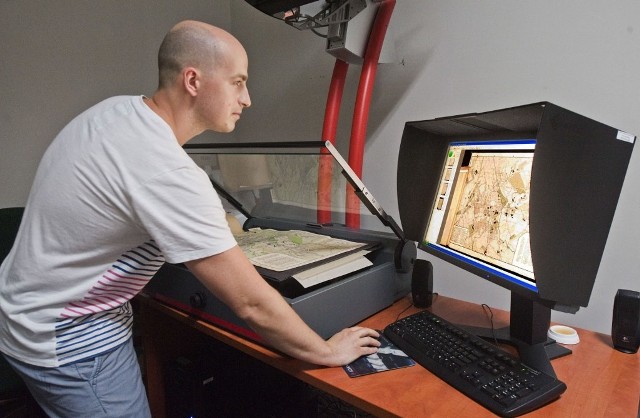 Grzegorz Andryszak, kierownik oddziału digitalizacji w koszalińskim Archiwum Państwowym, skanuje jeden z dokumentów.