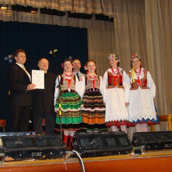 Radny Bukowski (pierwszy z lewej)  na scenie z przedstawicielkami starszej grupy tanecznej.