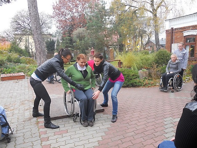 Agnieszka Leszczyńska (na wózku) oraz Małgorzata Wasilewska i Izabela Stępniak pokazują, jak pomóc przy zjeździe, np. z krawężnika