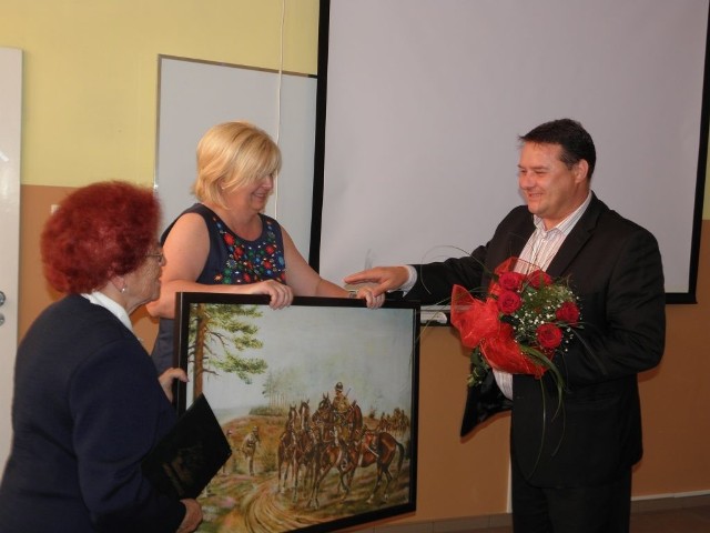 Kazimiera Szark i Alicja Kamińska wręczyły upominek Maciejowi Szmalcowi, dyrektorowi spółki "Nowa Energia", który kupił dla szkoły obrazy batalistyczne Zygfryda Szycha