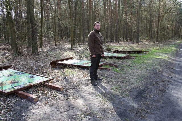 Mateusz Cieślakiewicz, leśniczy grudziądzkich Lasów Komunalnych, na tle zdewastowanych i poprzewracanych wczorajszej nocy tablic informacyjnych