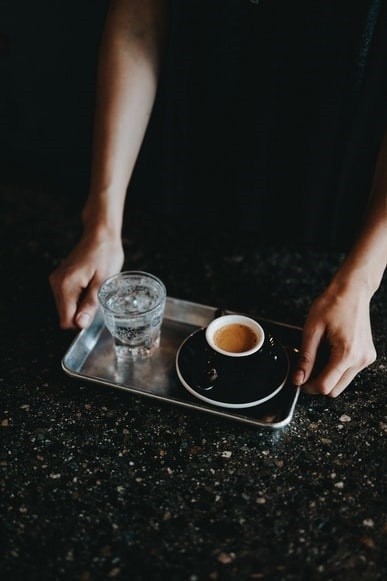 Espresso podaje się w małych filiżankach ze szklanką wody....