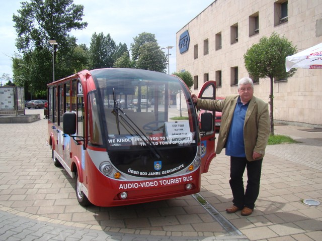 Janusz Gajdzicki obok swojego turystycznego busa przed dworcem PKP w Oświęcimiu.  Stąd przewozi turystów do Starego Miasta i Państwowego Muzeum Auschwitz-Birkenau