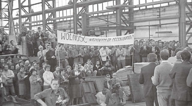 Wiec w Towimorze, gdzie latem 1980 roku zaczęła się toruńska „Solidarność”. Fotografia została zrobiona podczas obchodów pierwszej rocznicy tamtych wydarzeń. Na pierwszym planie z aparatem Adam Miłoszewski