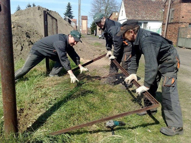 Paweł i Andrzej Szymendera i Krzysztof Czajkowski demontują stare ogrodzenie boiska.