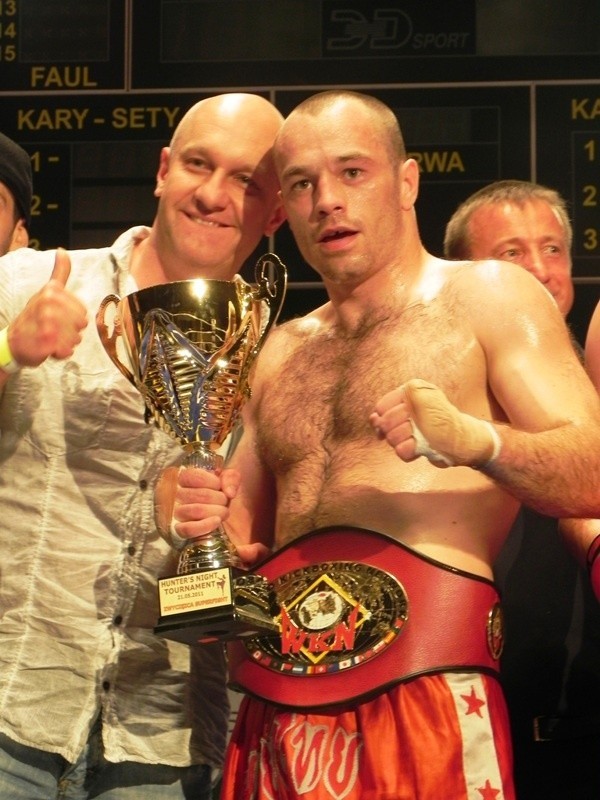 Łukasz Rambalski z jednym ze sponsorów i trofeami.