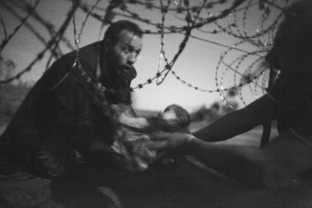 Czwartek 18.02Holandia, Amsterdam. Ogłoszenie wyników World Press Photo. Zwycięskie zdjęcie ukazuje mężczyznę - uchodźcę - przenoszącego dziecko pod ogrodzeniem granicznym na granicy serbsko - węgierskiej.