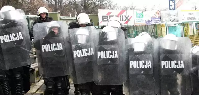 Policjanci ukryci za tarczami trenowali spychanie szalejących kibiców w narożnik sektora na stadionie żużlowym.