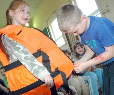 Najmłodsi uczniowie z &#8222;dwójki&#8221; uczyli się ubierać kamizelki ratunkowe. Marcin Lewandowski próbuje zapiąć kamizelkę Darii Jania.