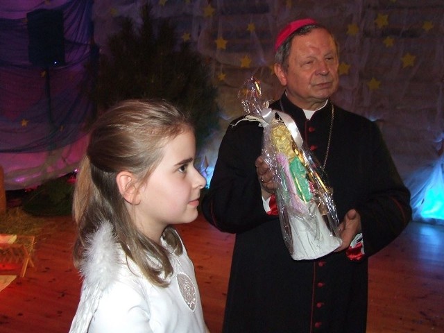 Ksiądz biskup Henryk Tomasik otrzymał od uczniów figurkę aniołka. Obok uczennica szkoły w Sadku Michalina Pastuszka.