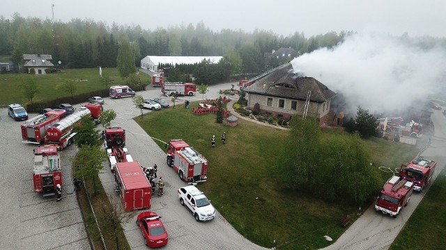 Pożar na terenie kompleksu Świętokrzyska Polana. Płonął dach budynku Lipowy Dwór. Do akcji ruszyło 20 zastępów Straży Pożarnej, w sumie 71 strażaków. Akcja gaszenia trwa od godziny 2.50. W chwili rozpoczęcia pożaru, nikogo nie było w obiekcie.Pożar w Lipowym Dworze. ZOBACZ FILM Z DRONAKilkudziesięciu strażaków walczyło w pożarem dachu Lipowego Dworu w Chrustach w gminie Zagnańsk. Płomienie zostały zauważone nocą z soboty na niedzielę przed godziną 3.Lipowy Dwór to murowany, kryty gontem budynek będący częścią Kompleksu Świętokrzyska Polana. Miejsce, w którym działa bistro, organizowane są imprezy okolicznościowe. O godzinie 2.50 w niedzielę służby ratunkowe dostały sygnał, że doszło tu do pożaru. W akcję zaangażowane zostały zastępy państwowej i ochotniczej straży pożarnej.O poranku kapitan Michał Świąder, zastępca komendanta miejskiego kieleckiej straży pożarnej mówił: - Na miejscu działa 71 strażaków. Pożarem objęta jest więźba dachowa i znaczna cześć dachu budynku. Akcja jest utrudniona, bo pokrycie dachu stanowi wielowarstwowy gont, którego ugaszenie jest możliwe dopiero w momencie przeprowadzenia prac rozbiórkowych konstrukcji dachu budynku.Część wyposażenia budynku udało się uratować. Przed płonącym dworkiem, na którego dachu działali strażacy w oczy rzucały się wyniesione ze środka krzesła.W niedzielne przedpołudnie ośrodek wydał oficjalne oświadczenie:Nad ranem doszło do pożaru jednego z budynków zlokalizowanych na terenie Kompleksu Świętokrzyska Polana. Najprawdopodobniej na skutek zwarcia instalacji elektrycznej spalił się pokryty gontem dach oraz poddasze Lipowego Dworu. W momencie wybuchu pożaru budynek był pusty. Nie ma osób poszkodowanych. Trwa dogaszanie części budynku oraz wstępne szacowanie strat. Ze względu na sytuację techniczną wszystkie atrakcje Kompleksu Świętokrzyska Polana będą dziś (niedziela, 5 maja) nieczynne. Znajdujący się w innej części terenu Ośrodek Rehabilitacyjny Polanika działa bez przeszkód – mówi Dyrektor Generalna Kompleksu Świętokrzyska Polana, Paulina Baran.