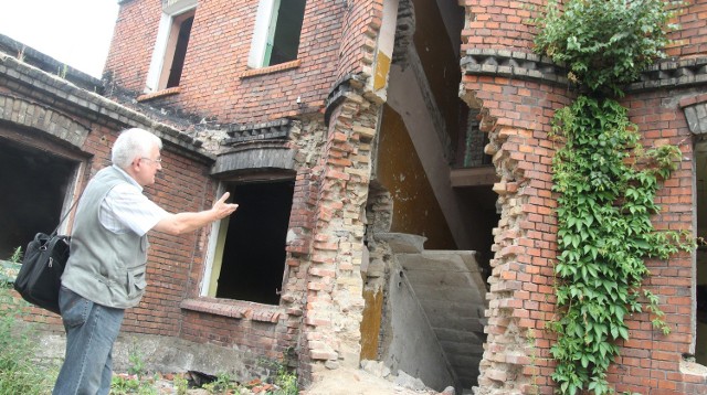 Krzysztof Cieczkiewicz pokazuje zniszczenia w kamienicy z kaflami przy ul. Łęgskiej. Kafle są od frontu domu.