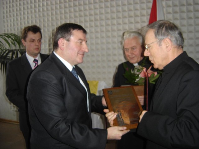 Wiktor Brzosko wręcza  akt nadania honorowego obywatelstwa księdzu prałatowi Józefowi Wyznerowi. W środku stoi ksiądz kanonik Piotr Faltyn