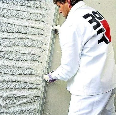 Pokrywanie ściany gipsem tynkarskim.