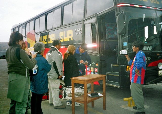 Autobus, kolejka do wejścia, stolik na którym za moment pojawi się lista pasażerów i gąbka nasączona tuszem do pobierania odcisków. Z boku mężczyzna z kamerą już zaczął pracę.