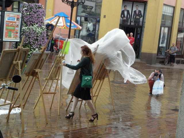 Justyna Barwina próbuje ratować obrazy przed deszczem