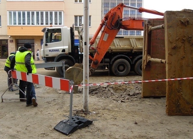 Łyżka koparki krusząca nawierzchnię uderzeniami w podłoże.