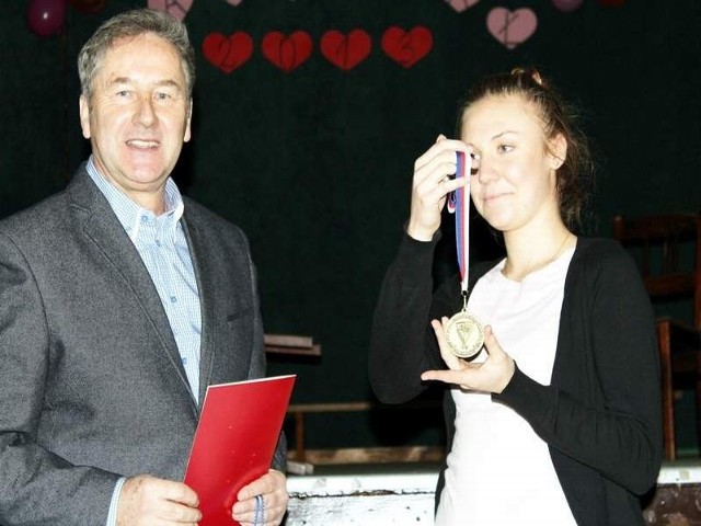 Szczęśliwa Natalia prezentuje złoty medal, obok gratulujący dyrektor szkoły Piotr Sadowski