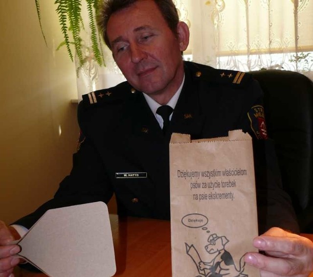 Wojciech Hatys, komendant Straży Miejskiej w Jędrzejowie, prezentuje torebki i łopatki, które rozdawane są za darmo.